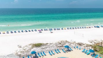 A beach resort with a swimming pool, sun loungers, and umbrellas.