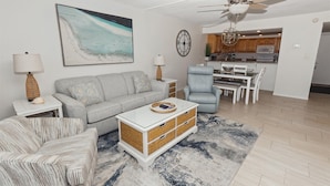 A living room with a grey sofa, a striped armchair, a white coffee table, and a ceiling fan.