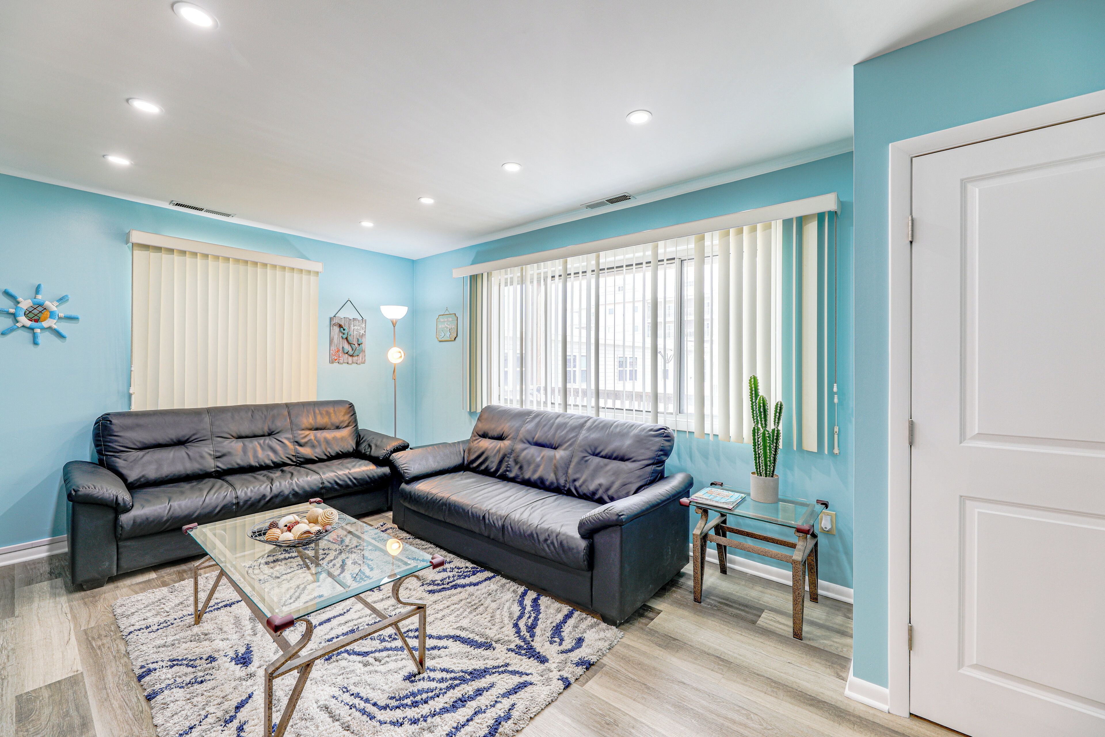 A living room with a sectional sofa, a glass coffee table, a small side table, and a door.