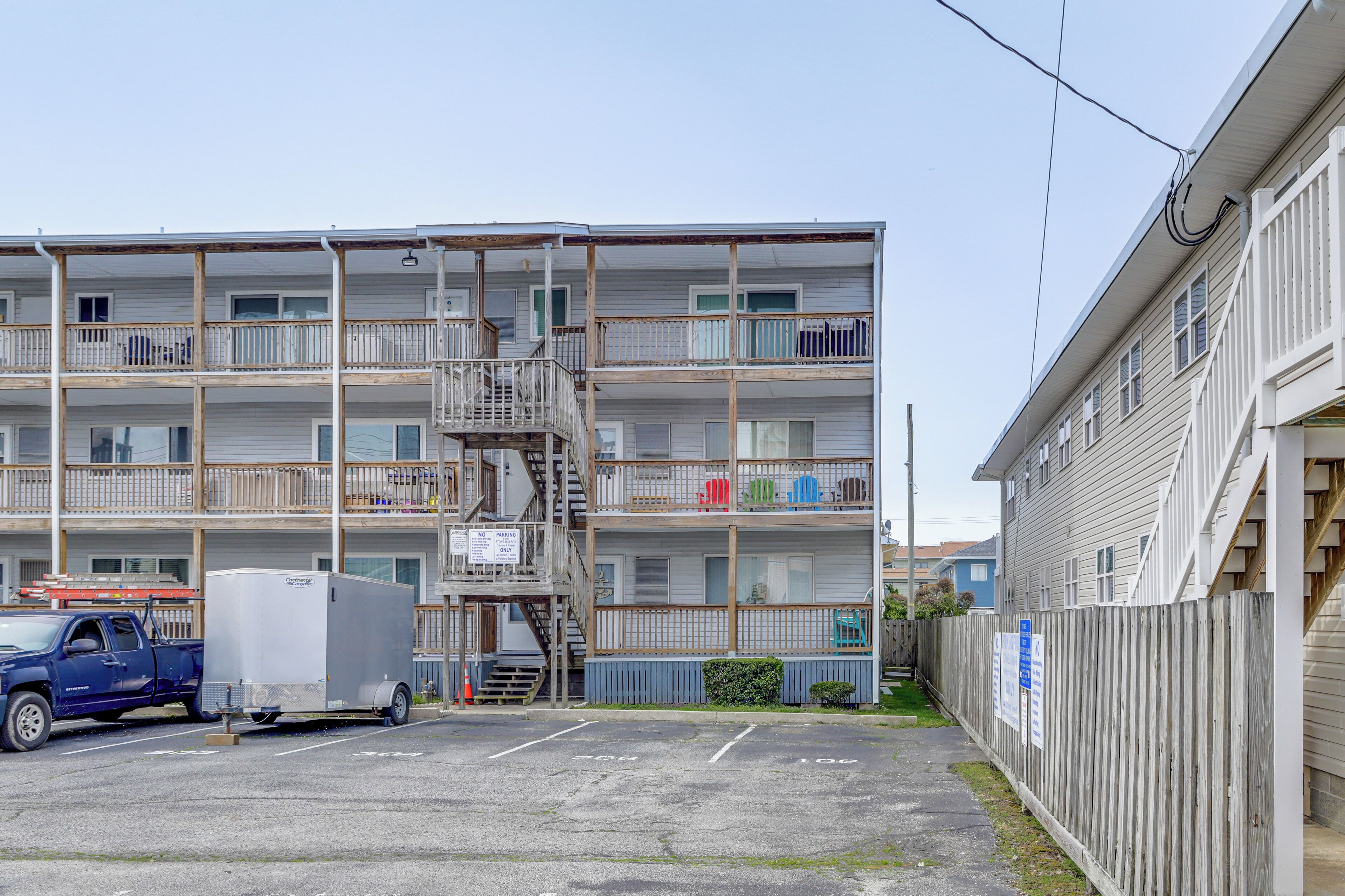 A multi-story building with balconies, a parking lot, and a truck.
