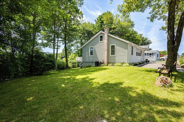 A two-story house with a front yard, a bench, and a tree. - Modern Terryville Cottage w/ Deck & Lake View! (Terryville)