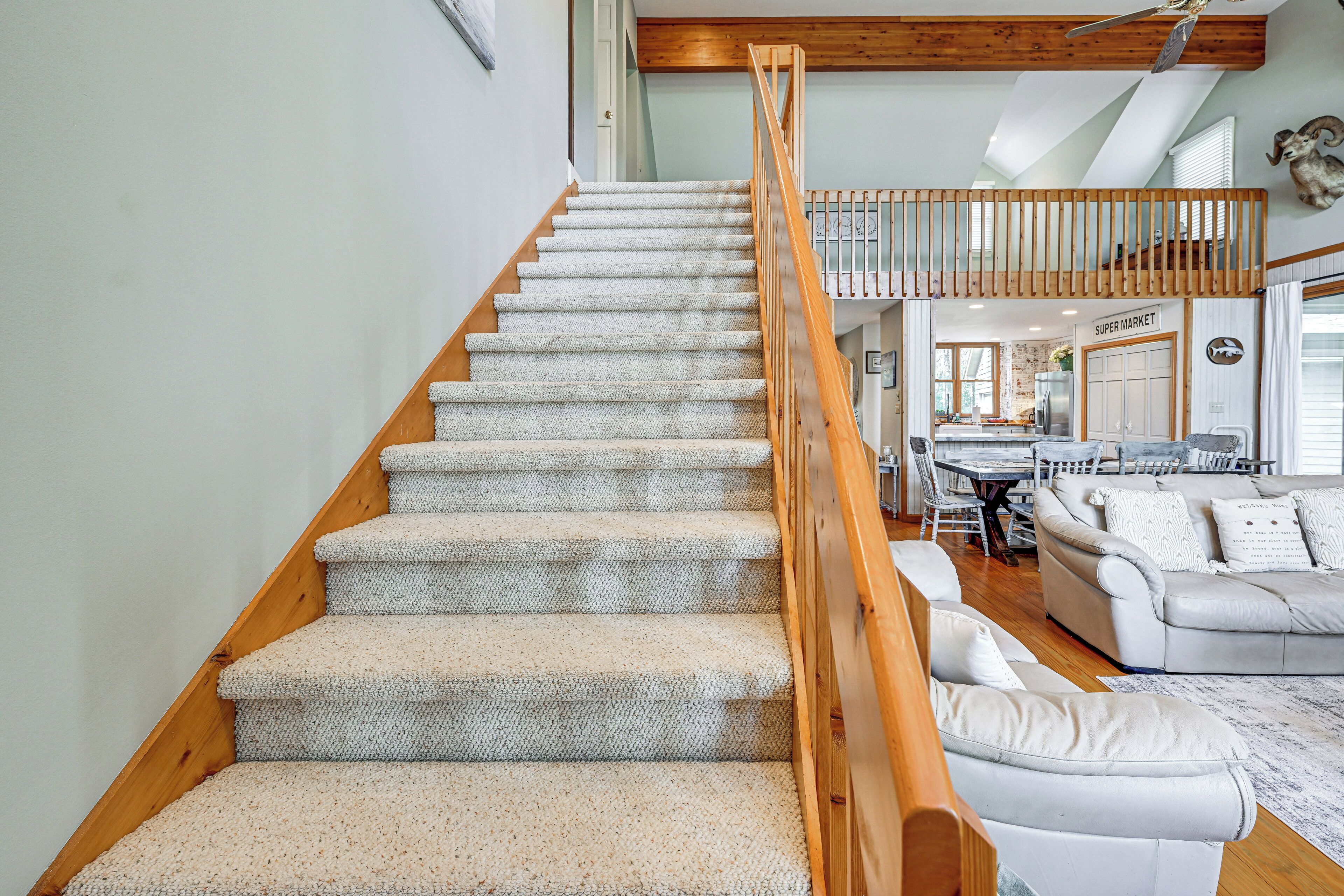 A staircase with a wooden handrail leading to a loft area with a dining table and chairs.
