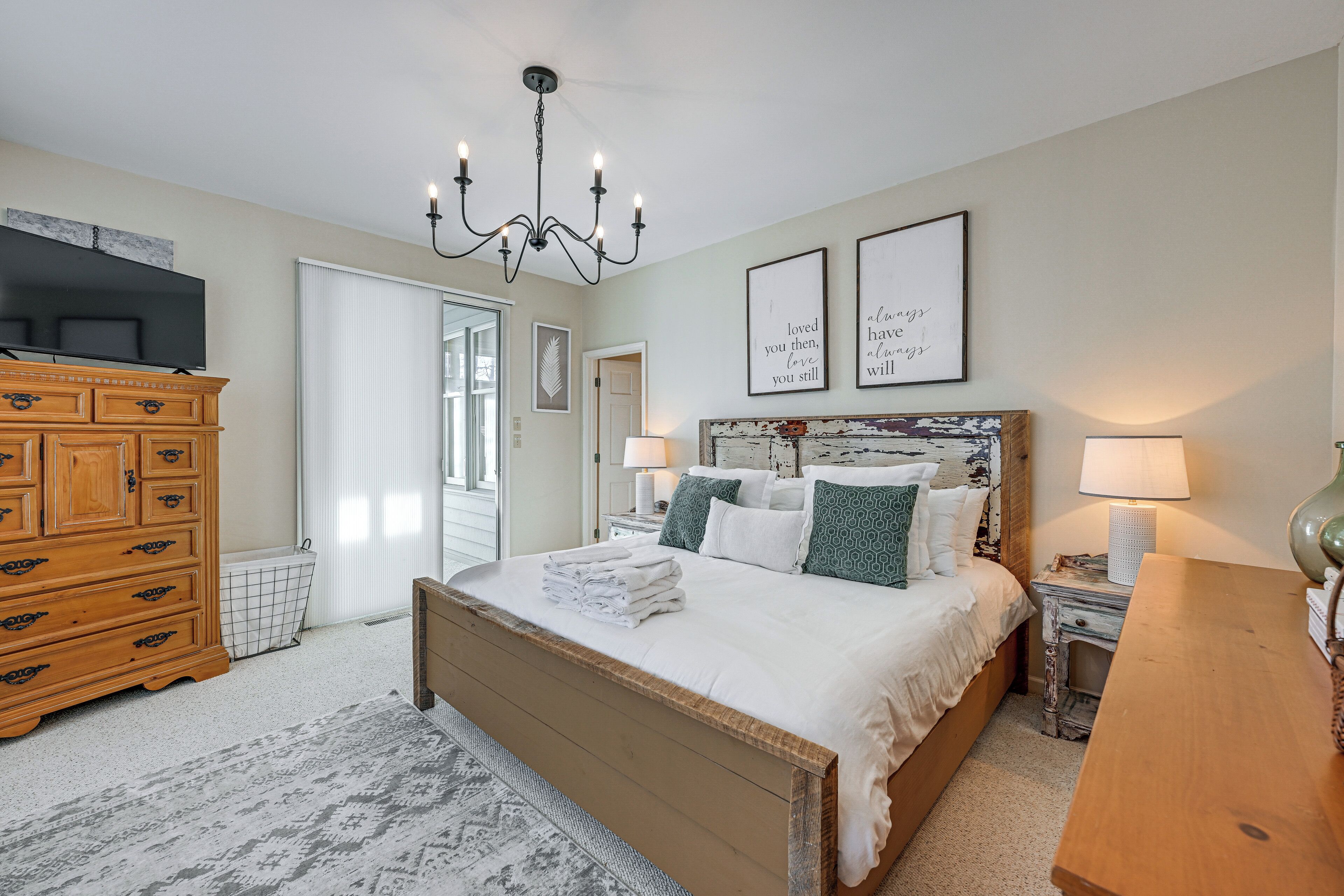 A bedroom with a large bed, wooden dresser, and a television on a stand.