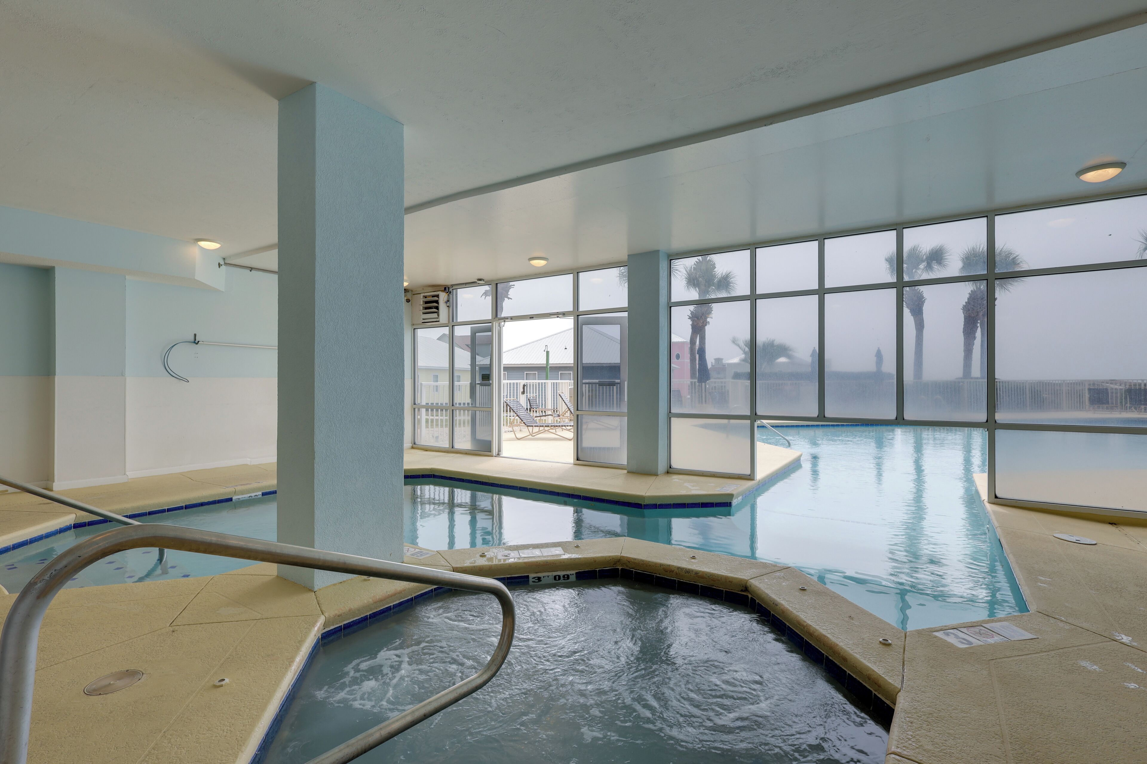 An indoor swimming pool with clear glass walls, a visible pool deck, and a lifeguard chair.