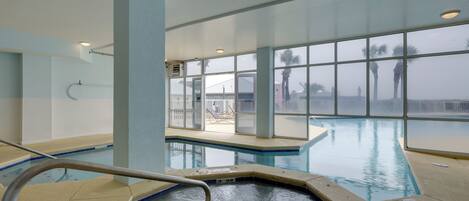 An indoor swimming pool with clear glass walls, a visible pool deck, and a lifeguard chair.