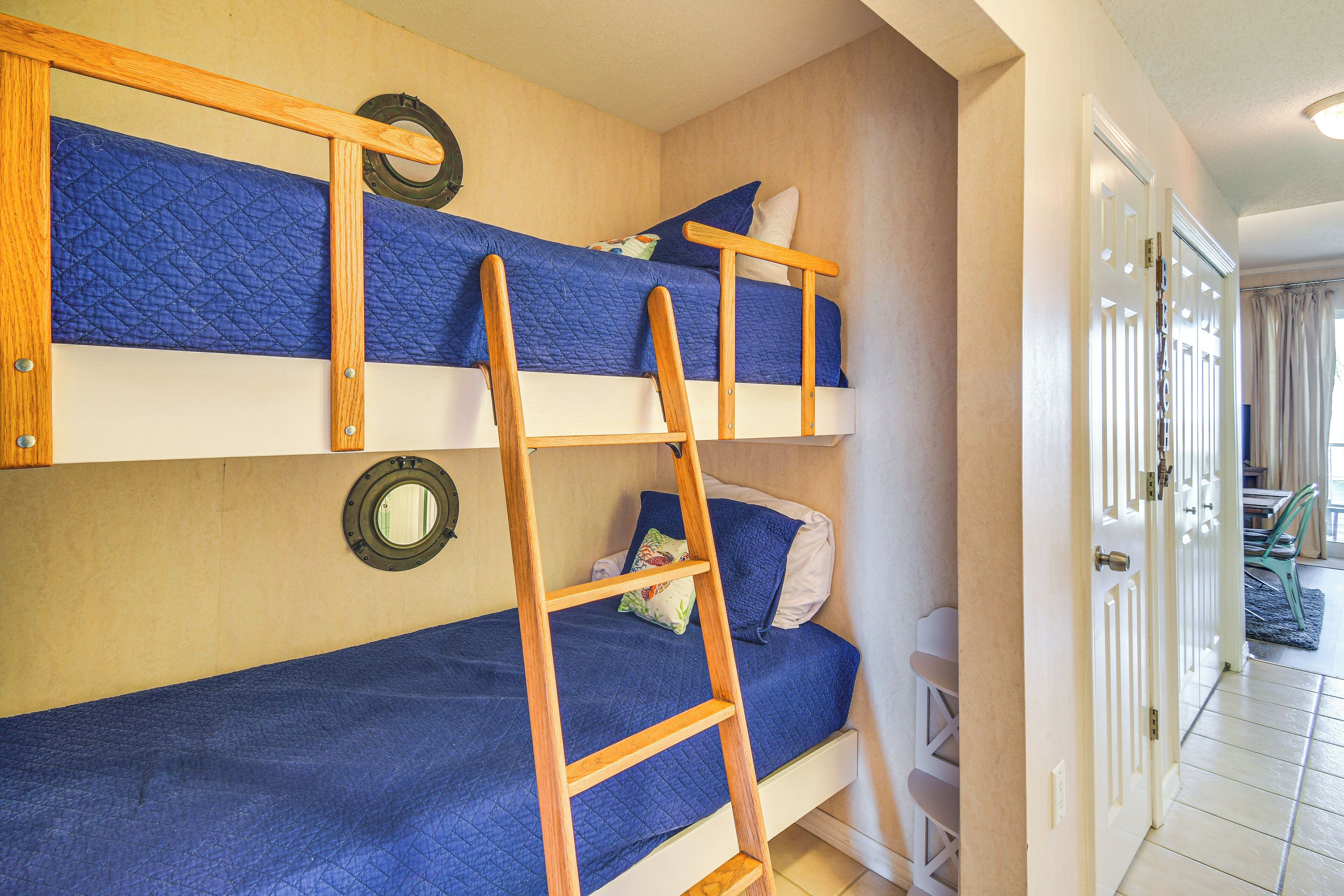 A bunk bed room with a ladder, a door, and a window.