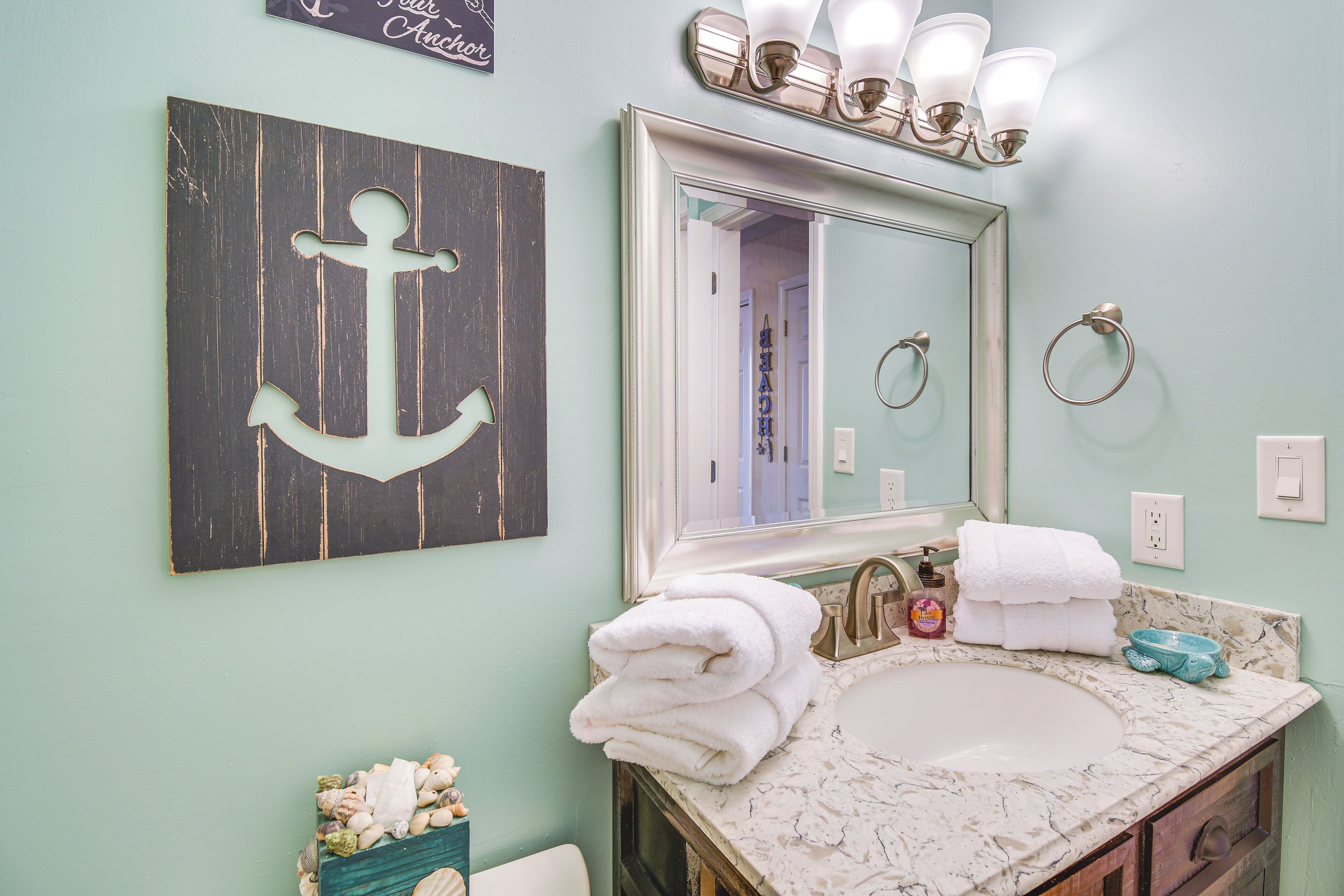 A bathroom with a sink, mirror, towels, and decorative items.