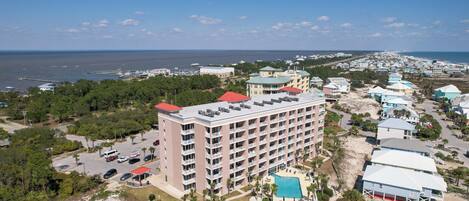 A multi-story hotel with a rooftop pool, surrounded by a beach and ocean views.