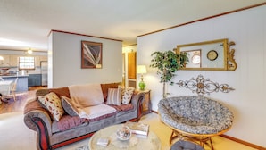 A living room with a sofa, a round coffee table, and a patterned armchair. - Fairfield Bay Getaway < 10 Mi to Boating & Hiking (Fairfield Bay)