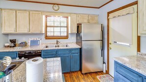 A kitchen with wooden cabinets, a stainless steel refrigerator, a sink, and a window with blinds. - Fairfield Bay Getaway < 10 Mi to Boating & Hiking (Fairfield Bay)