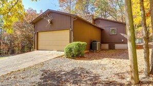 A two-story house with a garage, a small front yard with a bush, and a gravel driveway. - Fairfield Bay Getaway < 10 Mi to Boating & Hiking (Fairfield Bay)