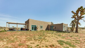 A desert-style building with a covered patio and a jarrad tree. - Quiet Oasis w/ Hot Tub: 21 Mi to Joshua Tree! (Landers)