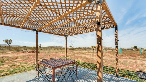 An outdoor patio with a wooden pergola, a table, and chairs. - Quiet Oasis w/ Hot Tub: 21 Mi to Joshua Tree! (Landers)