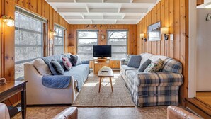A cozy living room with wooden walls, a large TV, two sofas, and a coffee table.