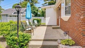 A patio with outdoor seating, a lamp post, and a small garden area.