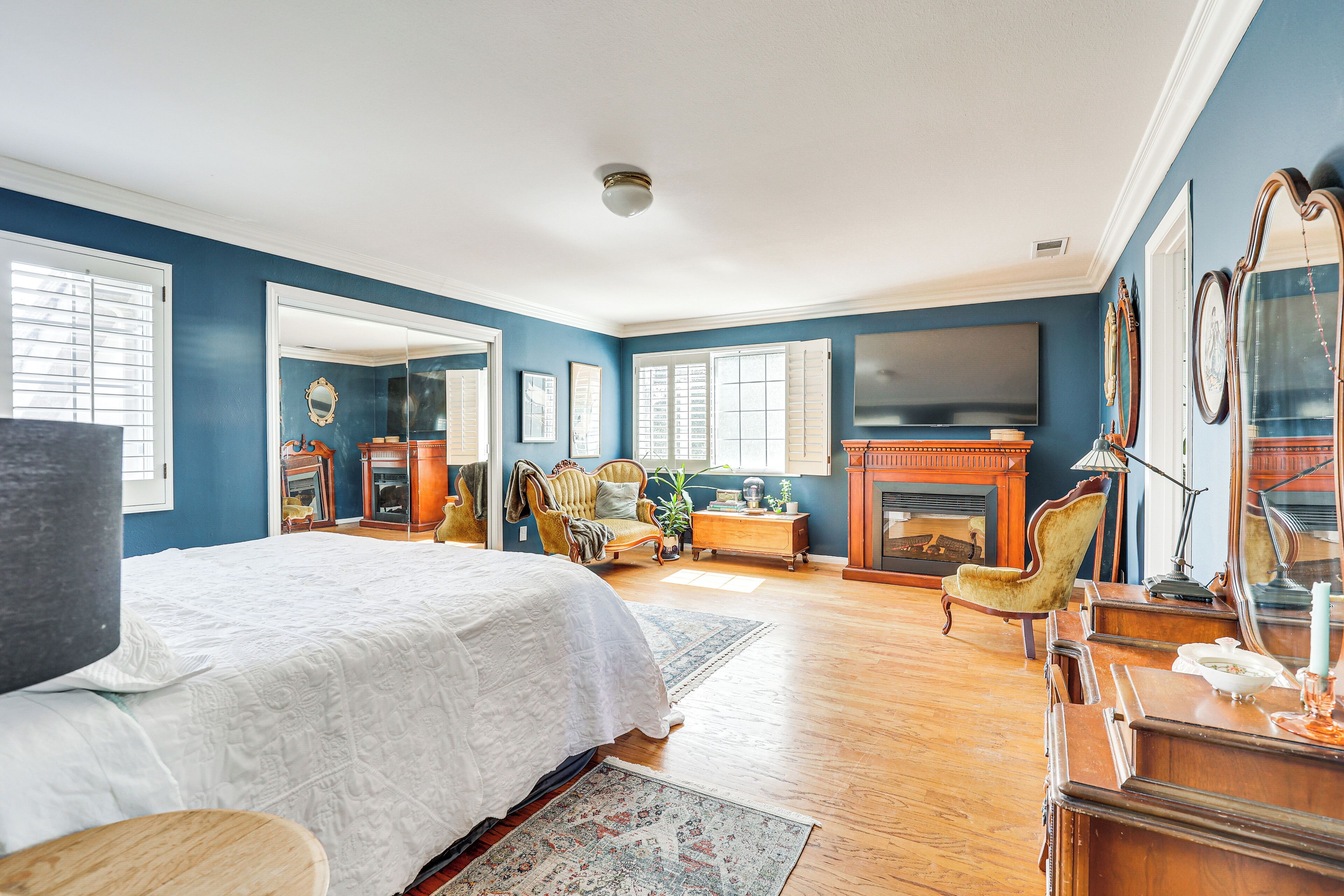 Une chambre spacieuse avec un grand lit, une cheminée et un téléviseur.