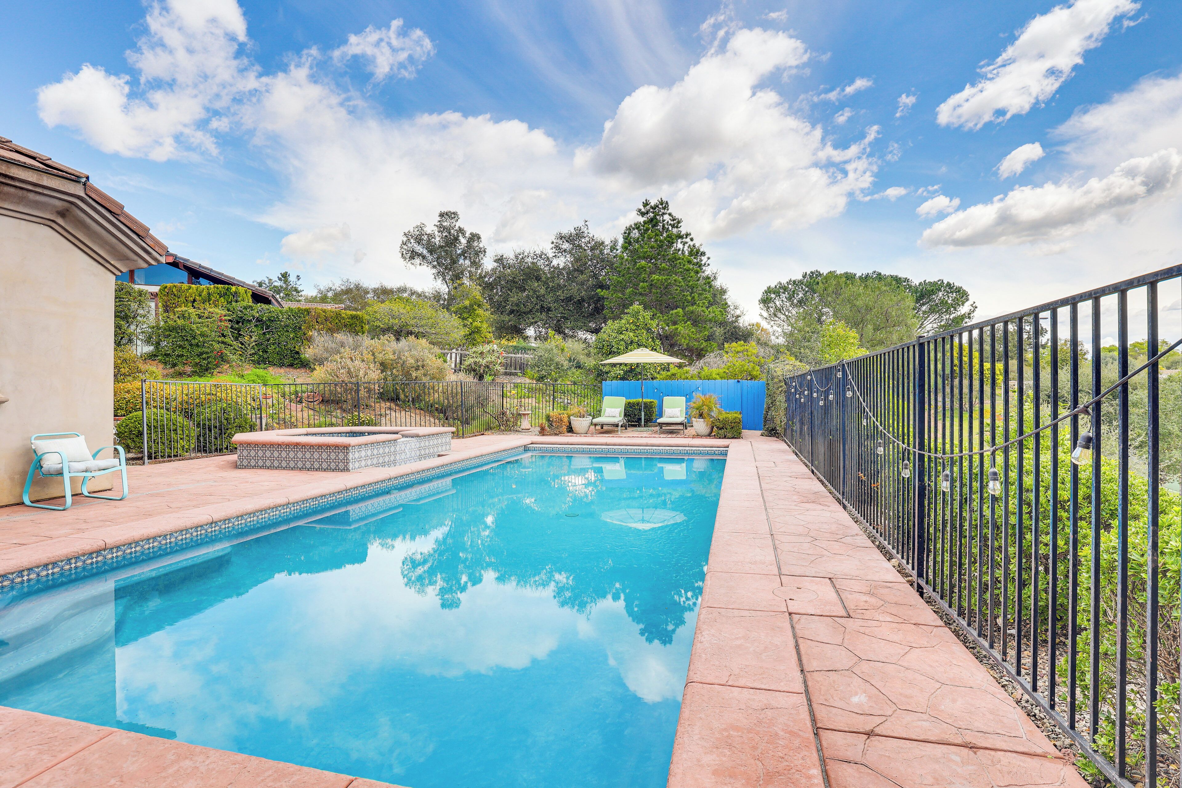 A rectangular swimming pool with a tiled edge, surrounded by a paved deck.