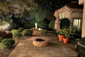 A patio area with a fire pit, outdoor furniture, and potted plants. - Escondido Home: Private Pool, 2 Grills & Fire Pit! (Escondido)