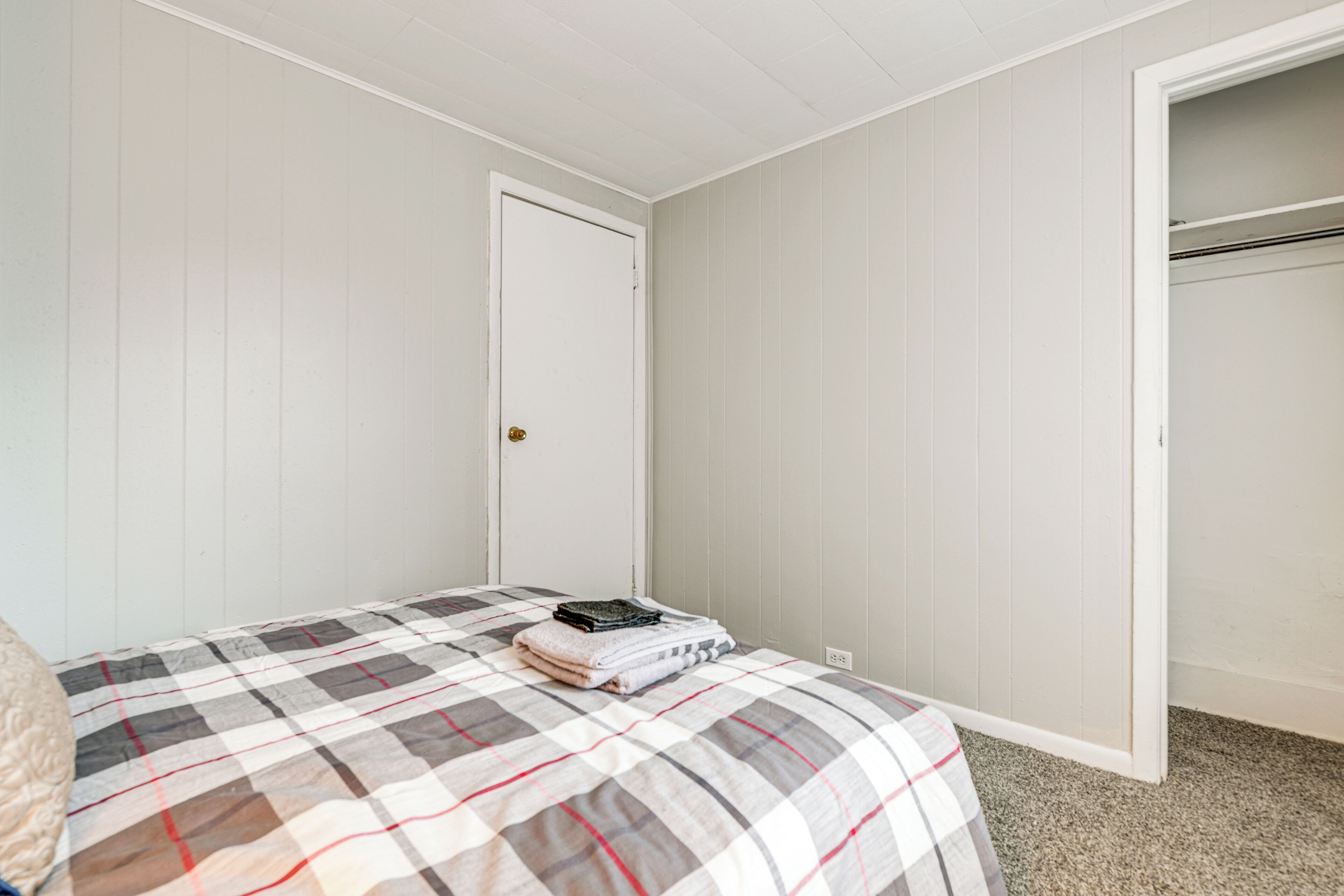 A bedroom with a bed, a closet, and a door.