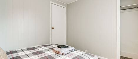 A bedroom with a bed, a closet, and a door.