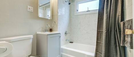 A bathroom with a toilet, sink, mirror, bathtub, and shower curtain.