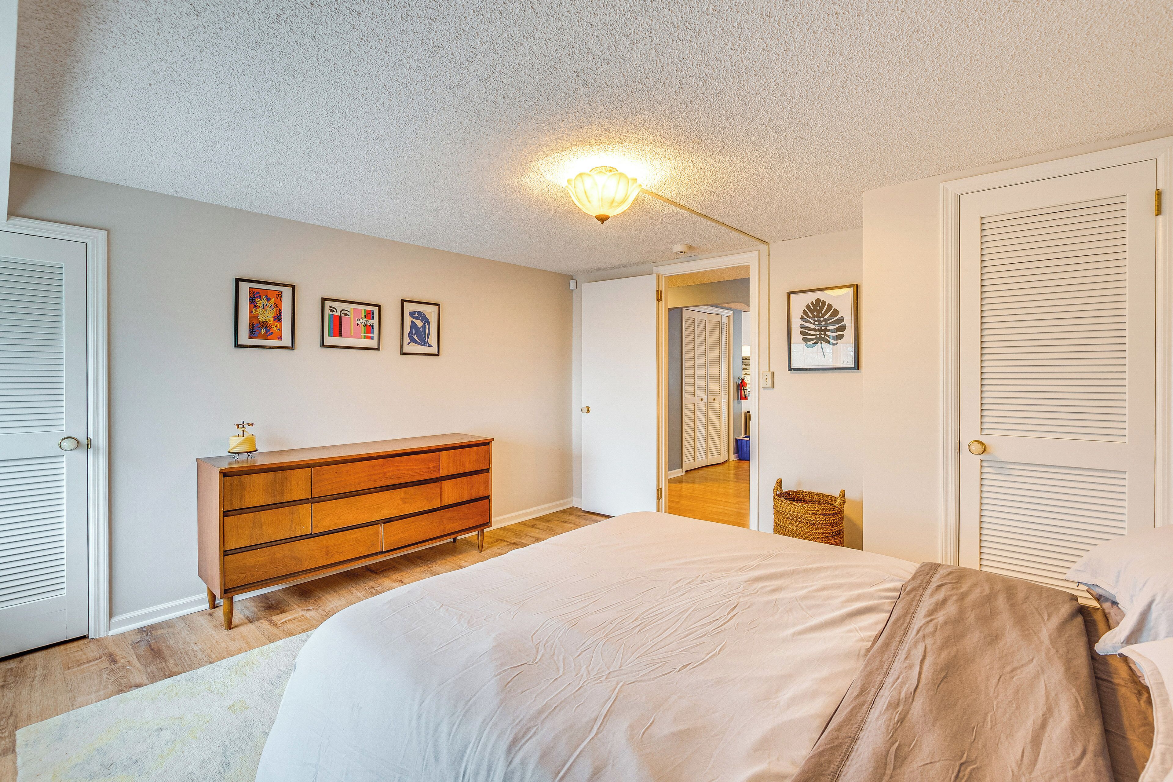 Un dormitorio con cama, cómoda y cuadro en la pared.