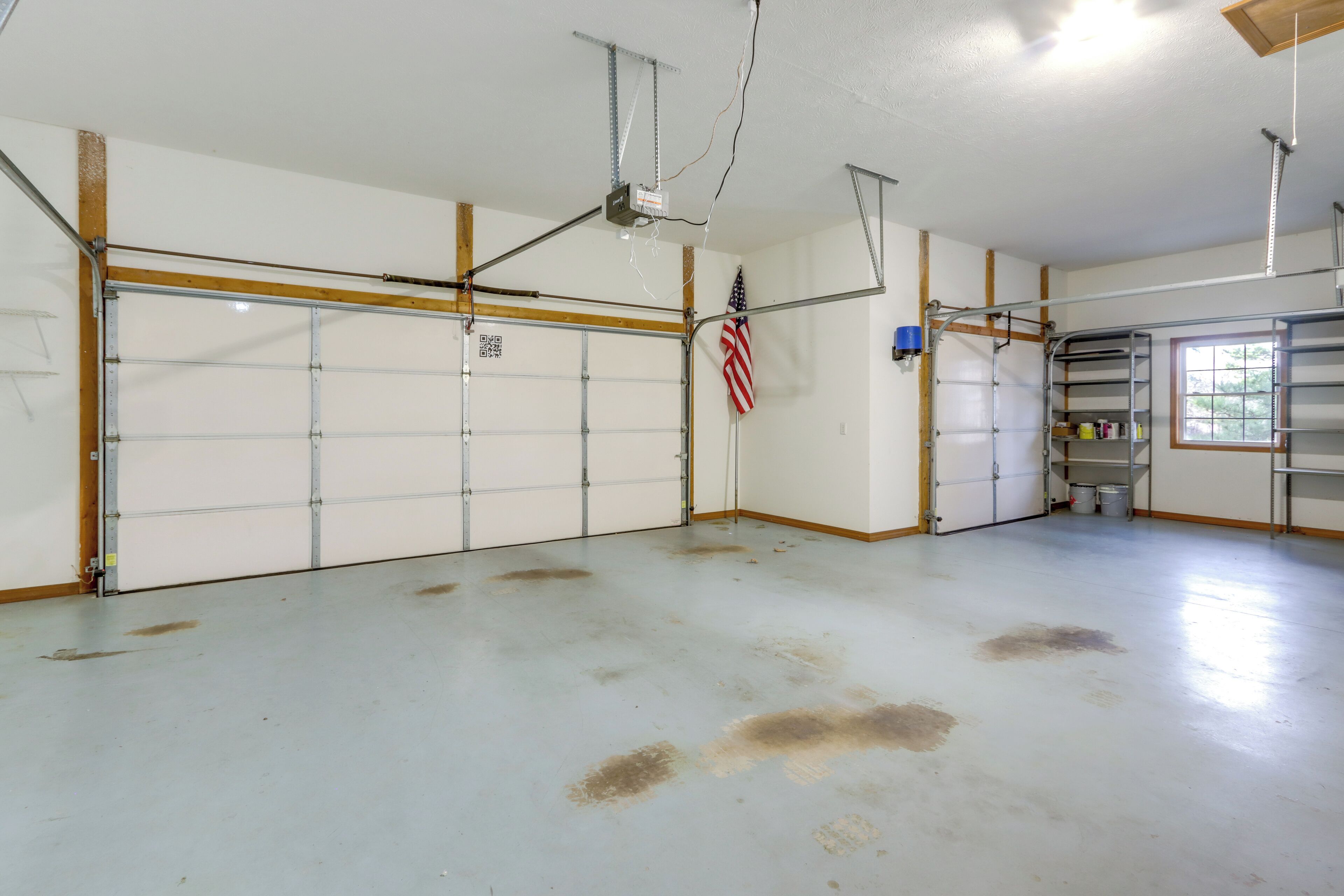Un garage avec un sol propre et blanc, et un grand drapeau américain accroché au mur.