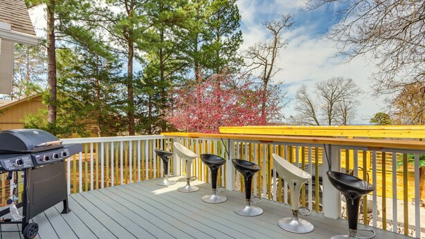 Une terrasse avec un barbecue et quatre tabourets de bar.