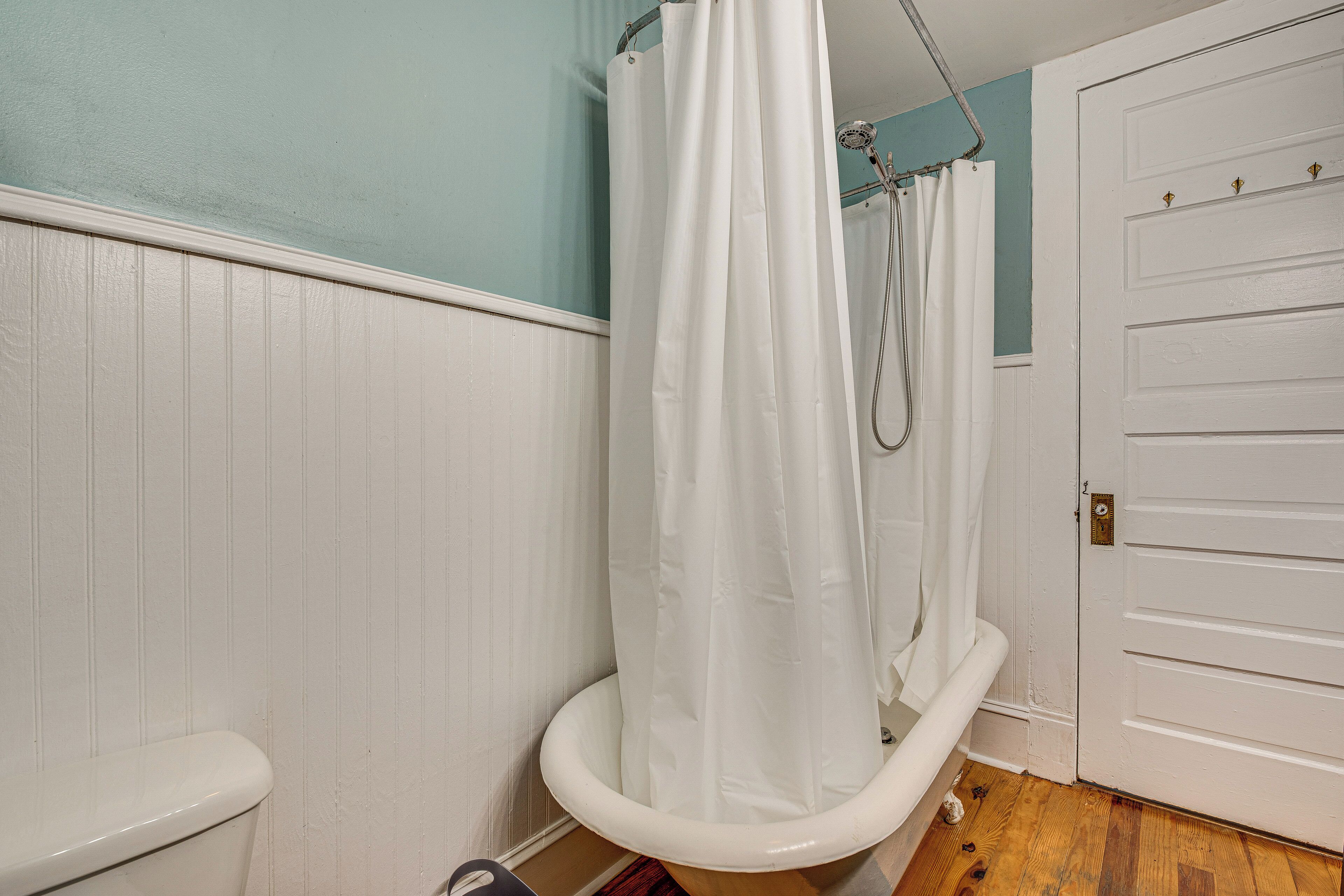 A bathroom with a white bathtub, a shower curtain, and a white door.