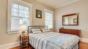 A bedroom with a bed, bedside tables, a dresser, and a mirror.