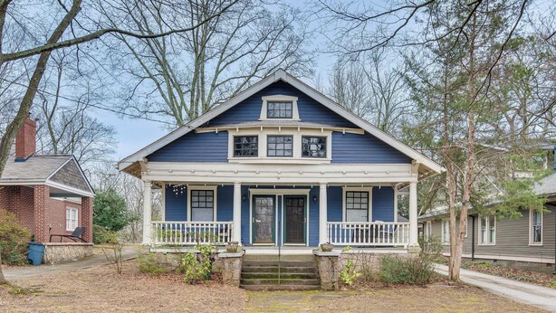A two-story house with a front porch, a chimney, and a small front yard.