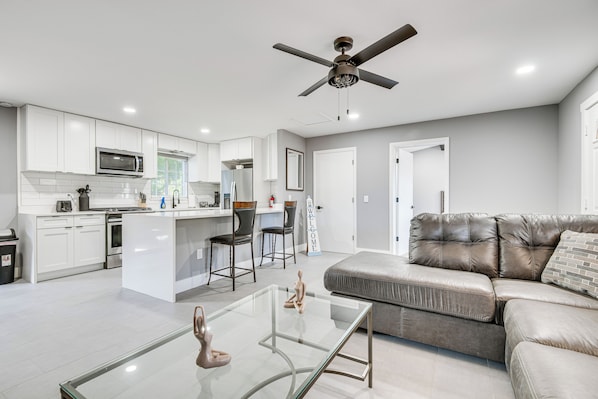 A modern kitchen with white cabinets, a central island, and a dining area with chairs.