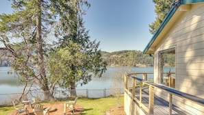 A lakeside property with a deck, outdoor seating, and a view of the lake. - Waterfront Washington Getaway w/ Hot Tub & Deck! (Olympia)