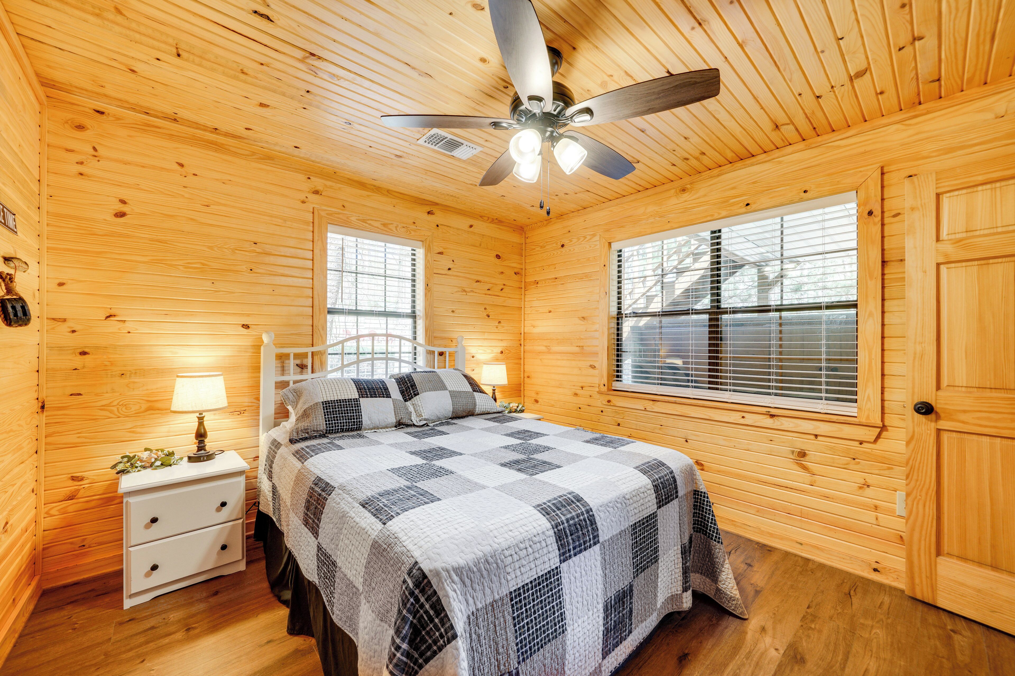 Ein Schlafzimmer einer Holzhütte mit Bett, Nachttisch, Lampe und Deckenventilator.