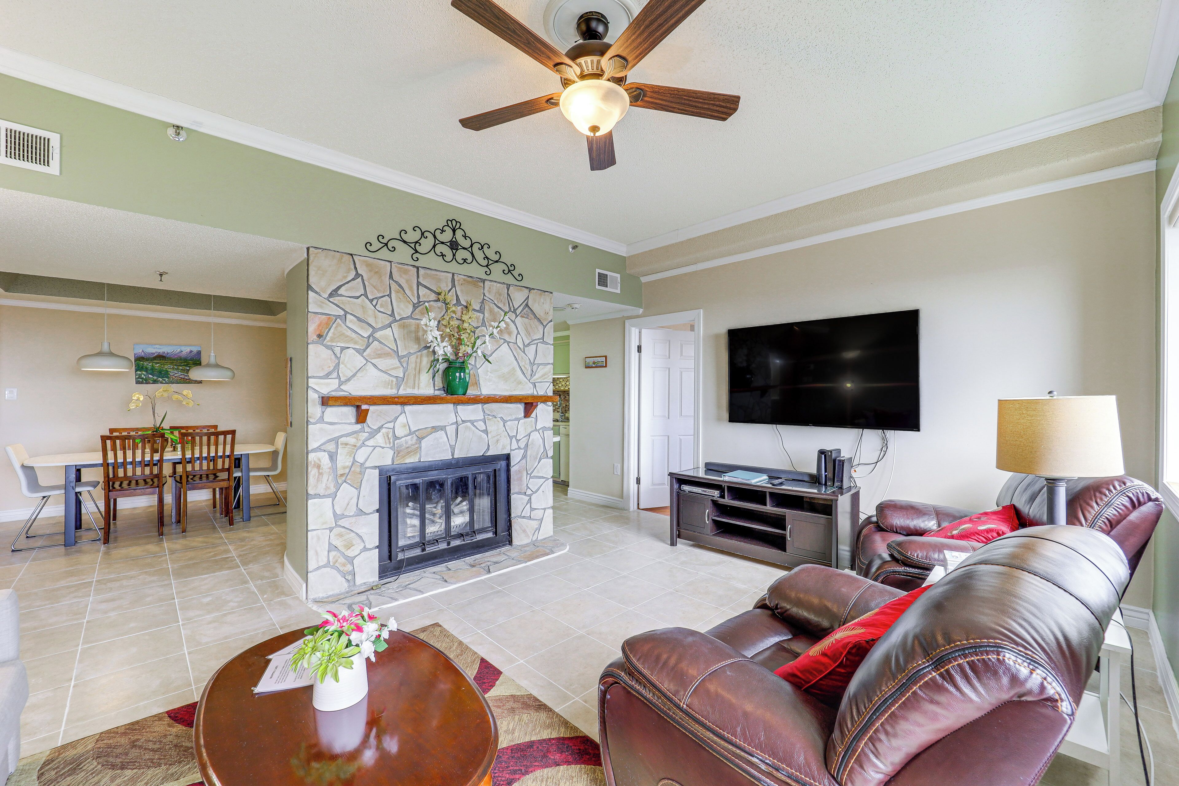 A living room with a stone fireplace, leather sofa, and a flat-screen TV.