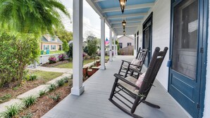 A porch with rocking chairs, a blue door, and a white railing. - Historical 1835 Home in Grand Coteau! (Sunset)
