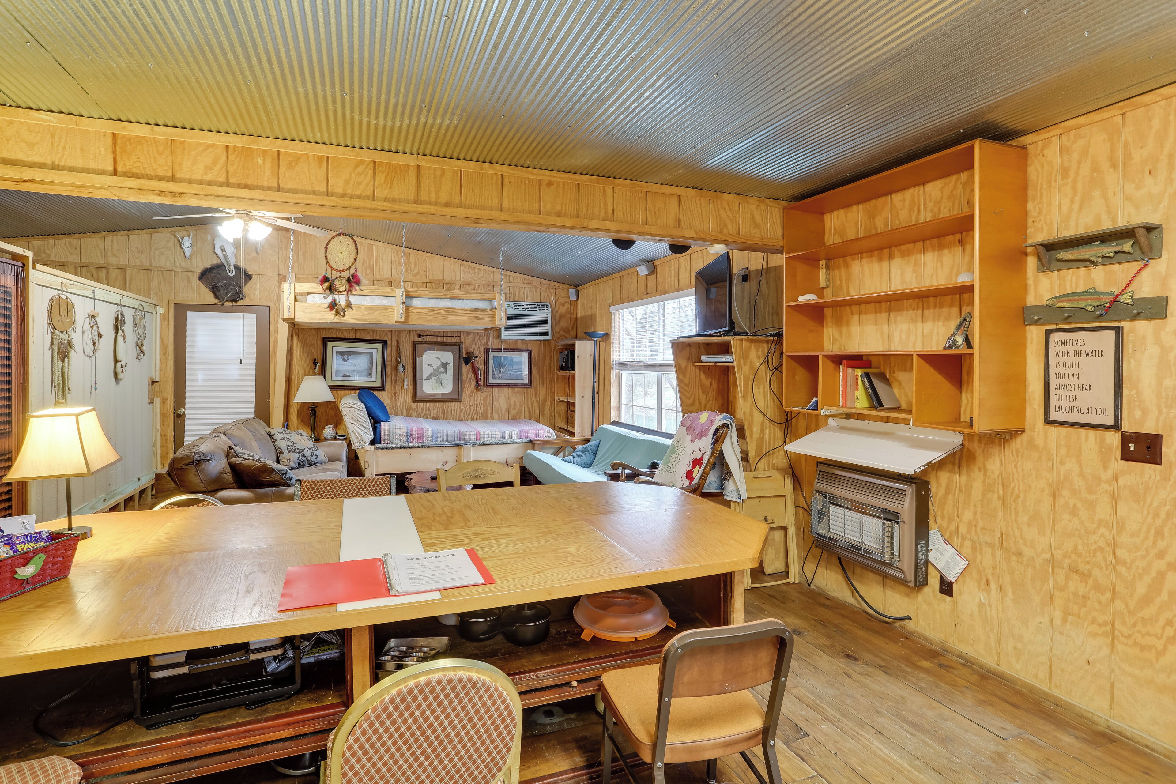 Ein gemütliches Blockhaus-Interieur mit einem Holzesstisch, Stühlen, einer Couch und einem Bücherregal.