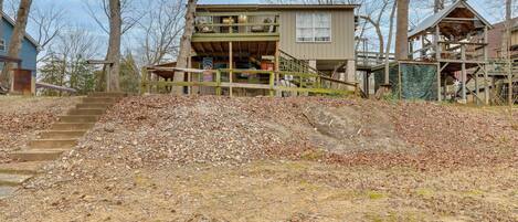 A two-story house with a wooden deck and a staircase leading to the entrance.