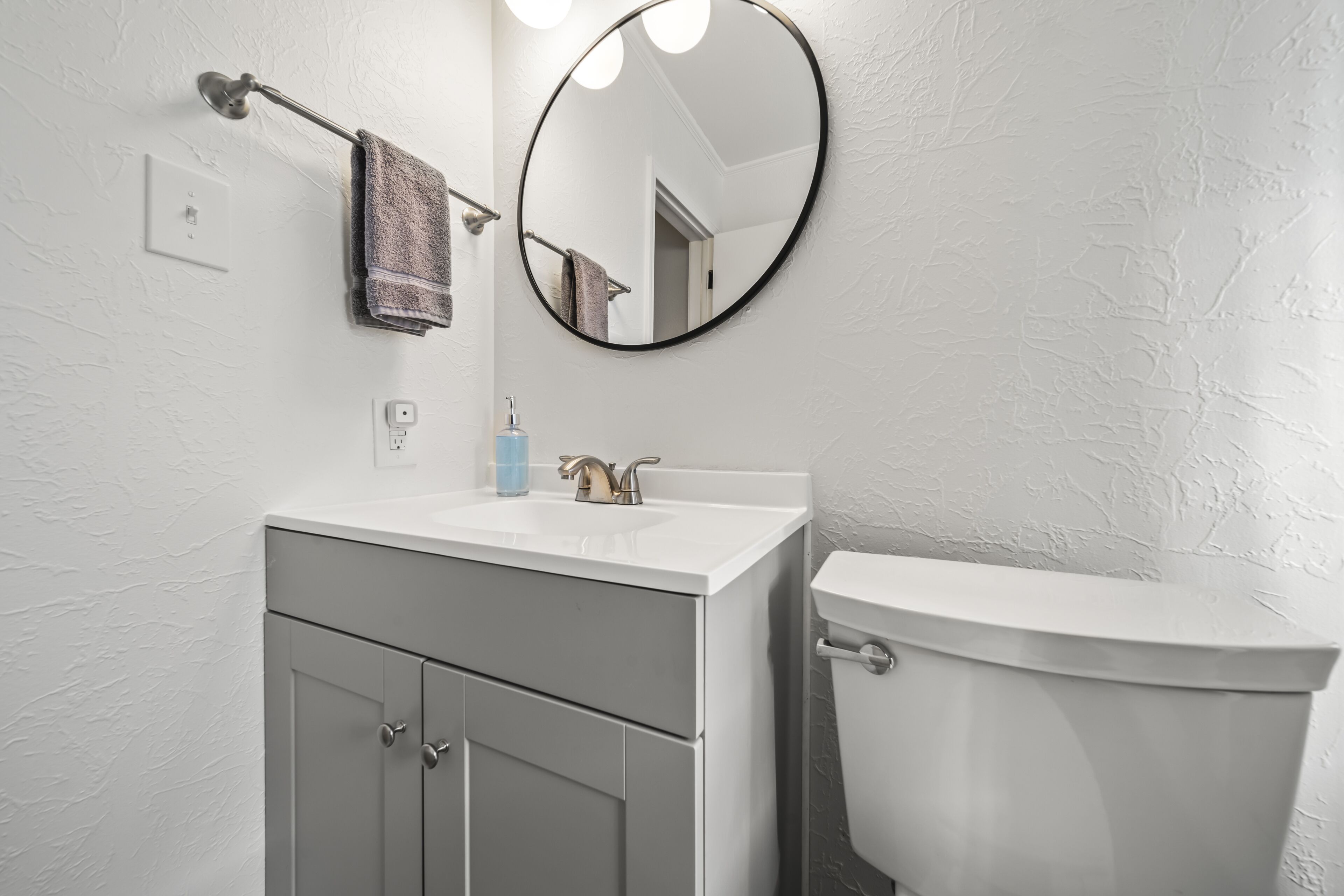 A bathroom with a white sink, a mirror, a towel, and a toilet.