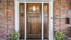 A wooden front door with a glass panel and a number plate, flanked by two potted plants. - 3BR/3BA 1940s Bungalow Near Expo Square. Pet friendly! (Tulsa)