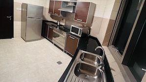 A modern kitchen with stainless steel appliances, a black countertop, and a large window. - AlRaef Luxury Apartments (Dubai)