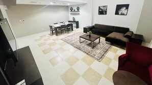 A modern living room with a brown sofa, a red armchair, and a dining area with a table and chairs. - AlRaef Luxury Apartments (Dubai)