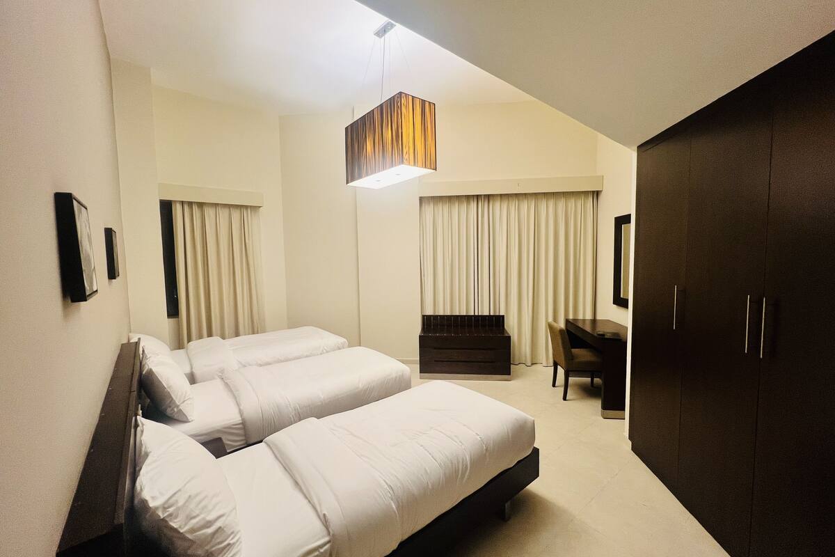 Ein Hotelzimmer mit zwei Betten, einem Schreibtisch, einem Kleiderschrank und einer Pendelleuchte.