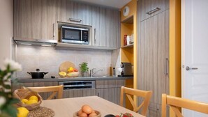 Una cocina moderna con armarios de madera, un microondas y una mesa de comedor puesta con frutas y verduras.