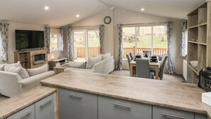 A modern kitchen with grey cabinets, a central island, and a dining area with a table and chairs.