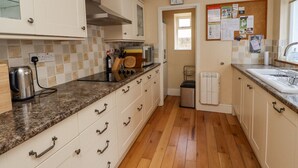 A kitchen with white cabinets, a stainless steel kettle, a microwave, and a sink. - Victoria House (Alnwick)