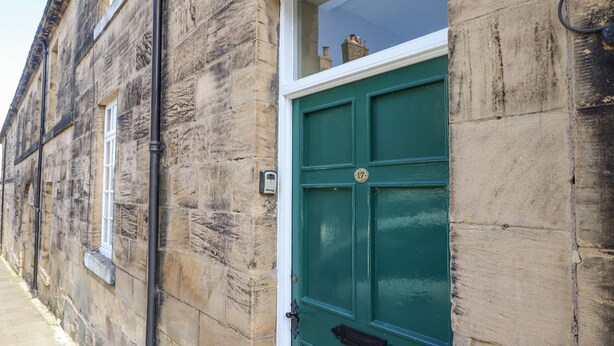 A stone building with a green door and a window. - Victoria House (Alnwick)