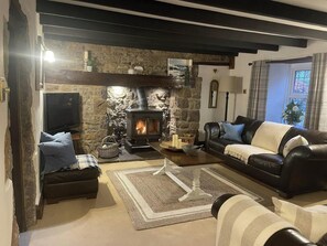A cozy living room with a stone fireplace, leather sofa, and a television.