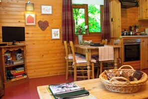 A cozy cabin interior with a wooden interior, a dining table with chairs, a television, and a kitchen area.