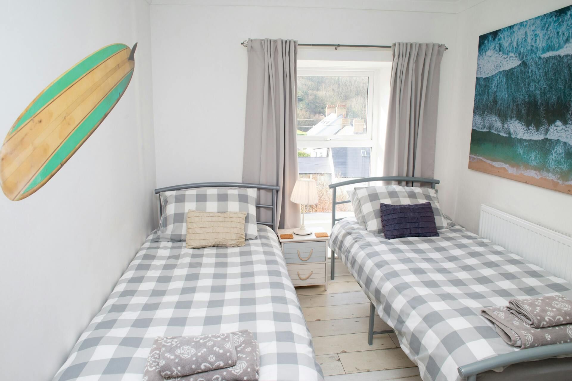 Single beds in triple bedroom with sea related artwork on the walls